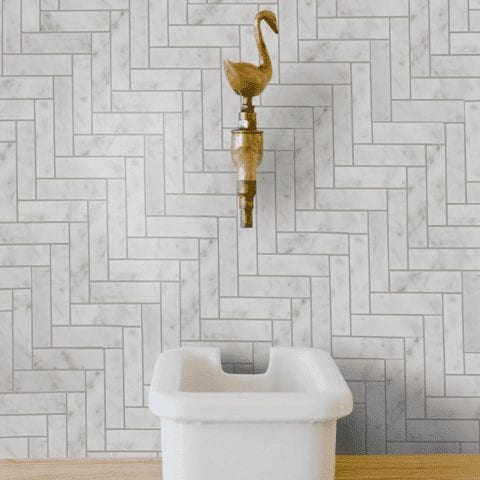 a bathroom backsplash with clé tile carrara subway tiles installed in a herringbone pattern