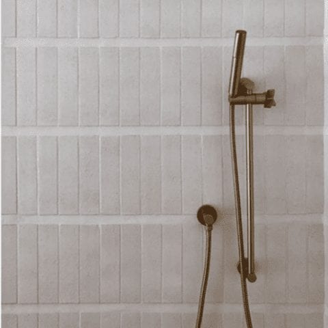 a shower wall with clé tile modern farmhouse brick tiles in cream gloss installed in stripes