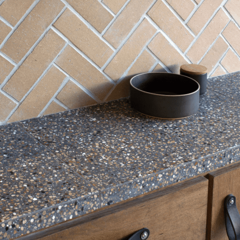 a kitchen countertop tiled with cle tile forage terrazzo large format squares in charcoal.