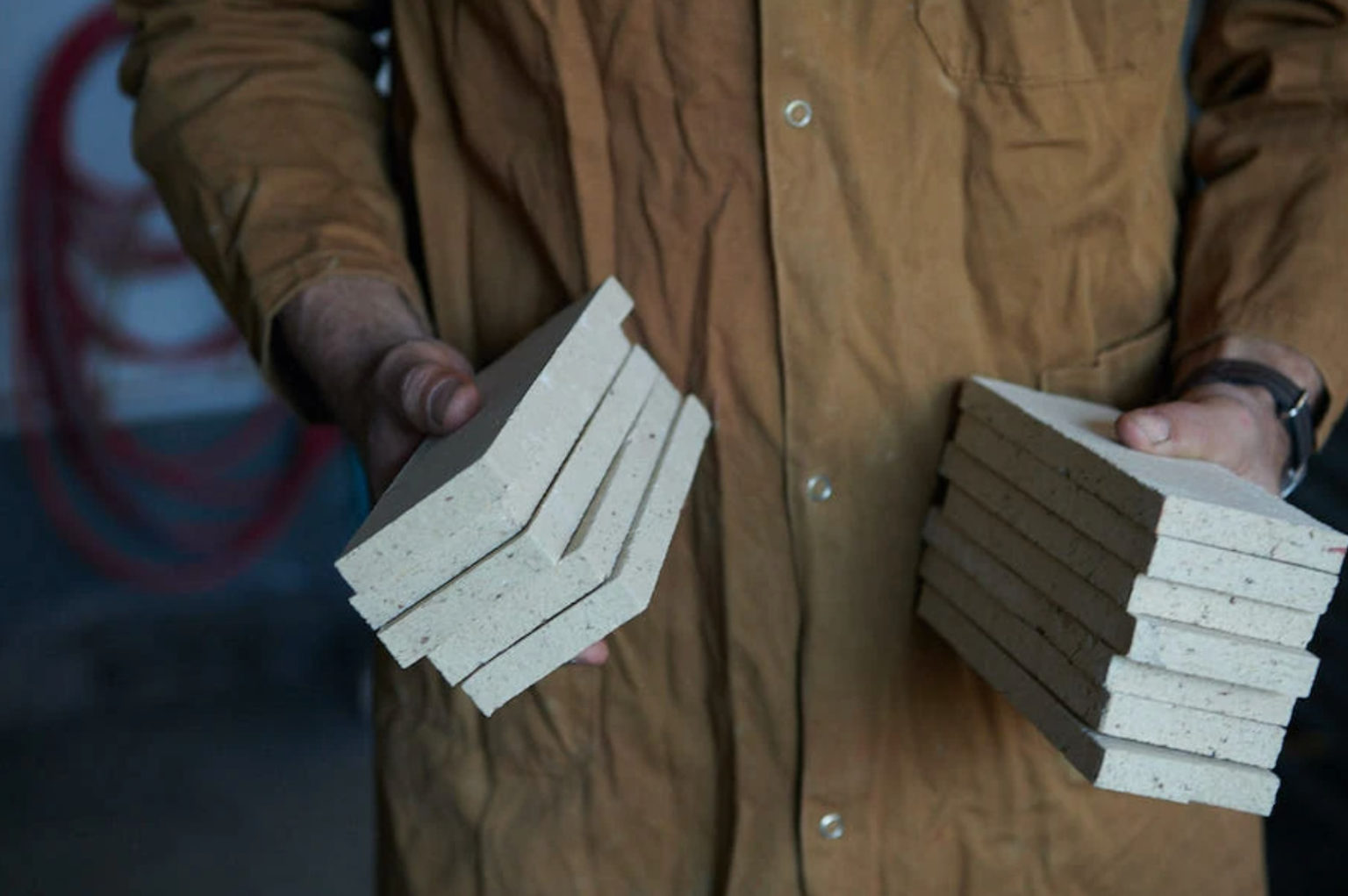 Eric Vandermolen holds two stacks of freshly fired tile in the clé guild studio.