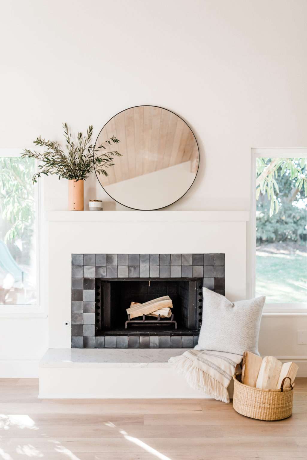 a bright white living room with a contrasting fireplace tiled in eastern earthenware zellige squares in smudge.